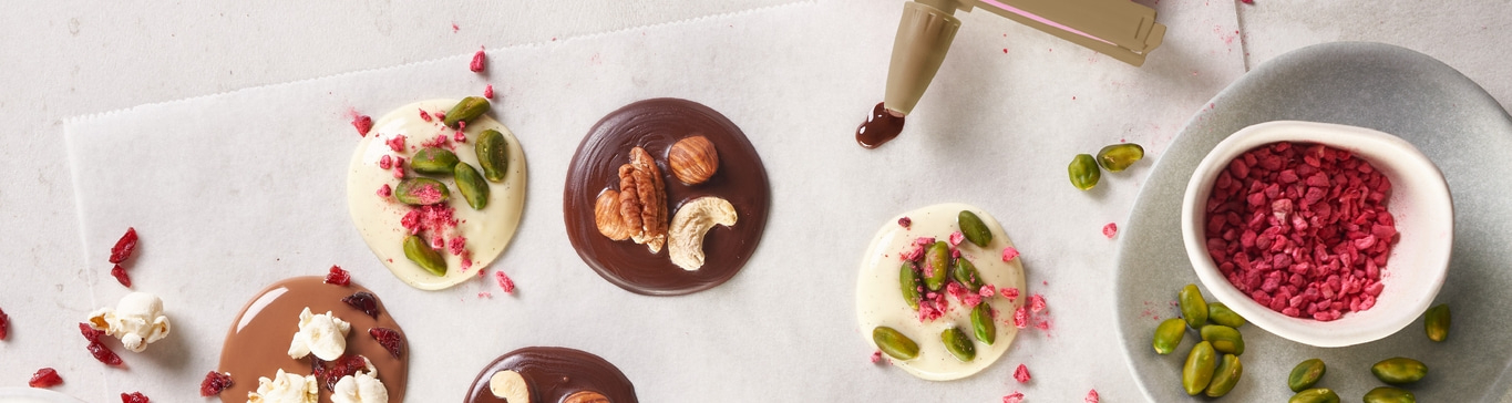 Cercles de chocolat avec noix et fruits décorés sur papier, gros plan.