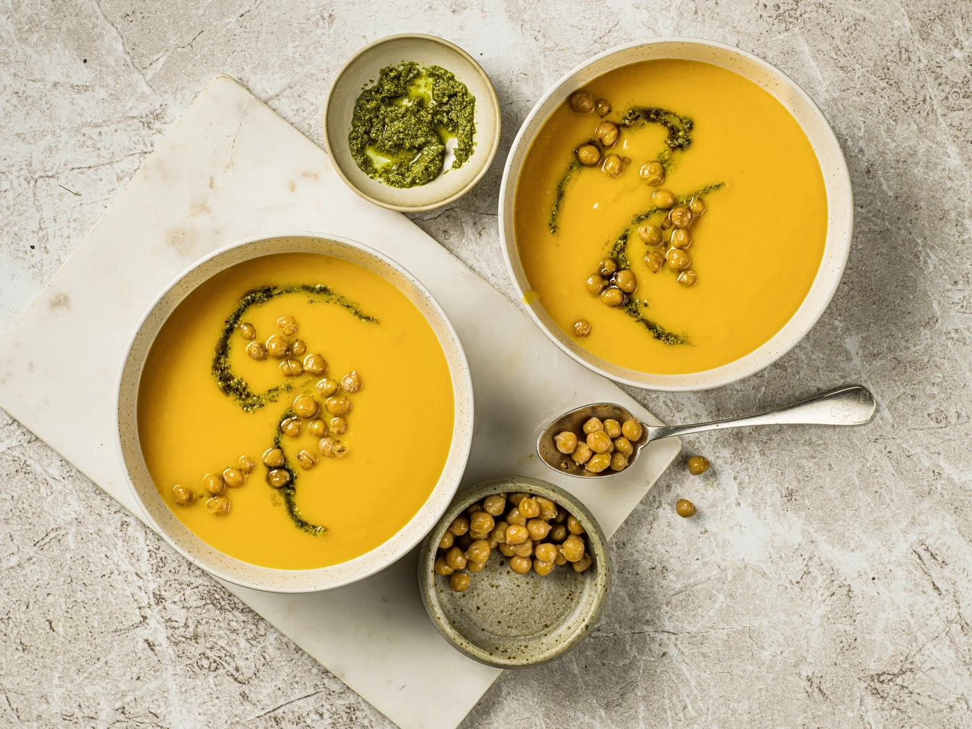 Deux bols de soupe avec pois chiches et pesto sur une table