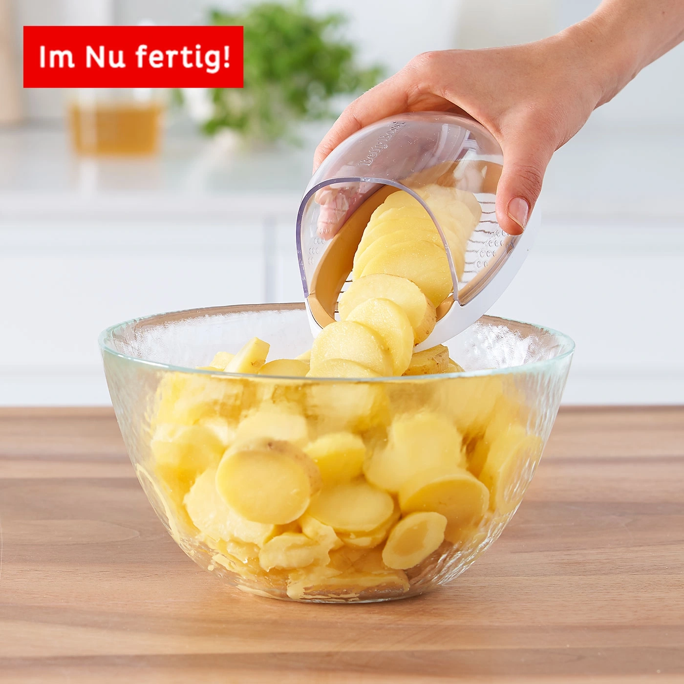 Kartoffelscheiben werden in eine Glasschüssel geschnitten, Küchenutensil, Essen zubereiten, Holzbrett
