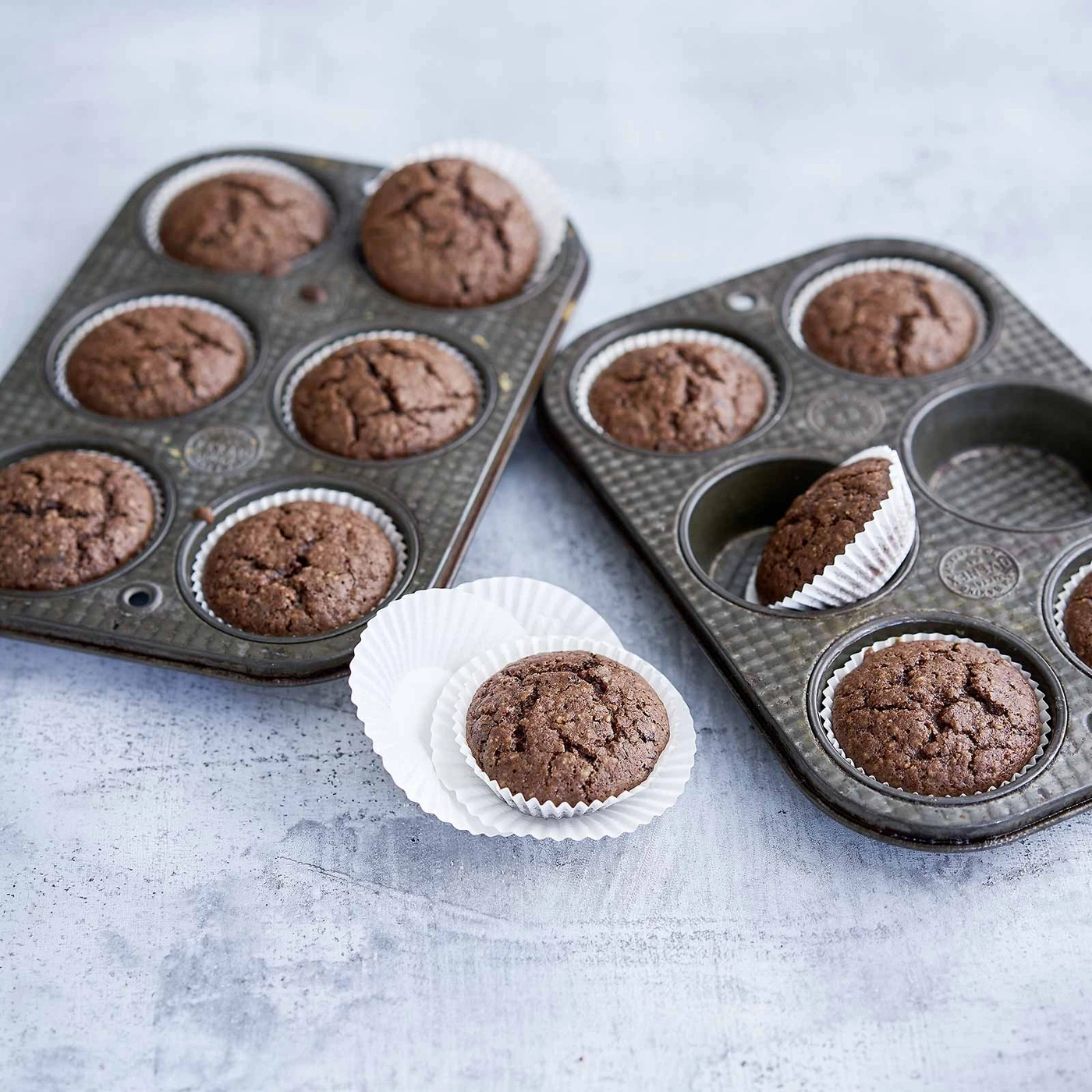 Schokoladenmuffins in Backformen auf grauem Untergrund, Nahaufnahme