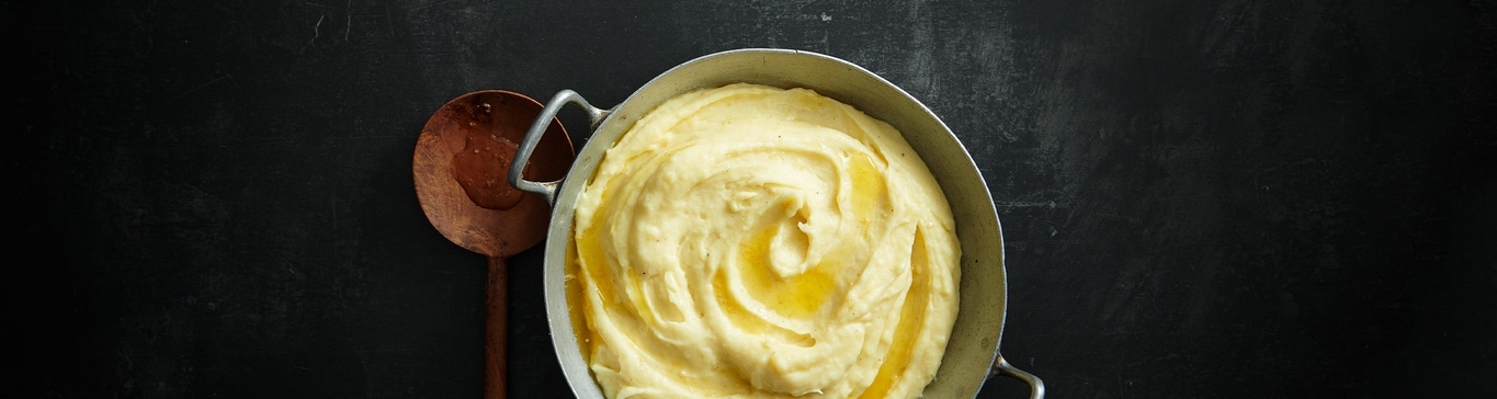 Kartoffelpüree in einer Schüssel mit einem Löffel auf einem schwarzen Hintergrund