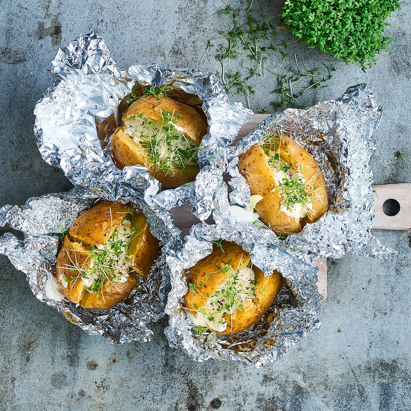Pommes de terre grillées en papillote avec herbes et sauce sur une planche