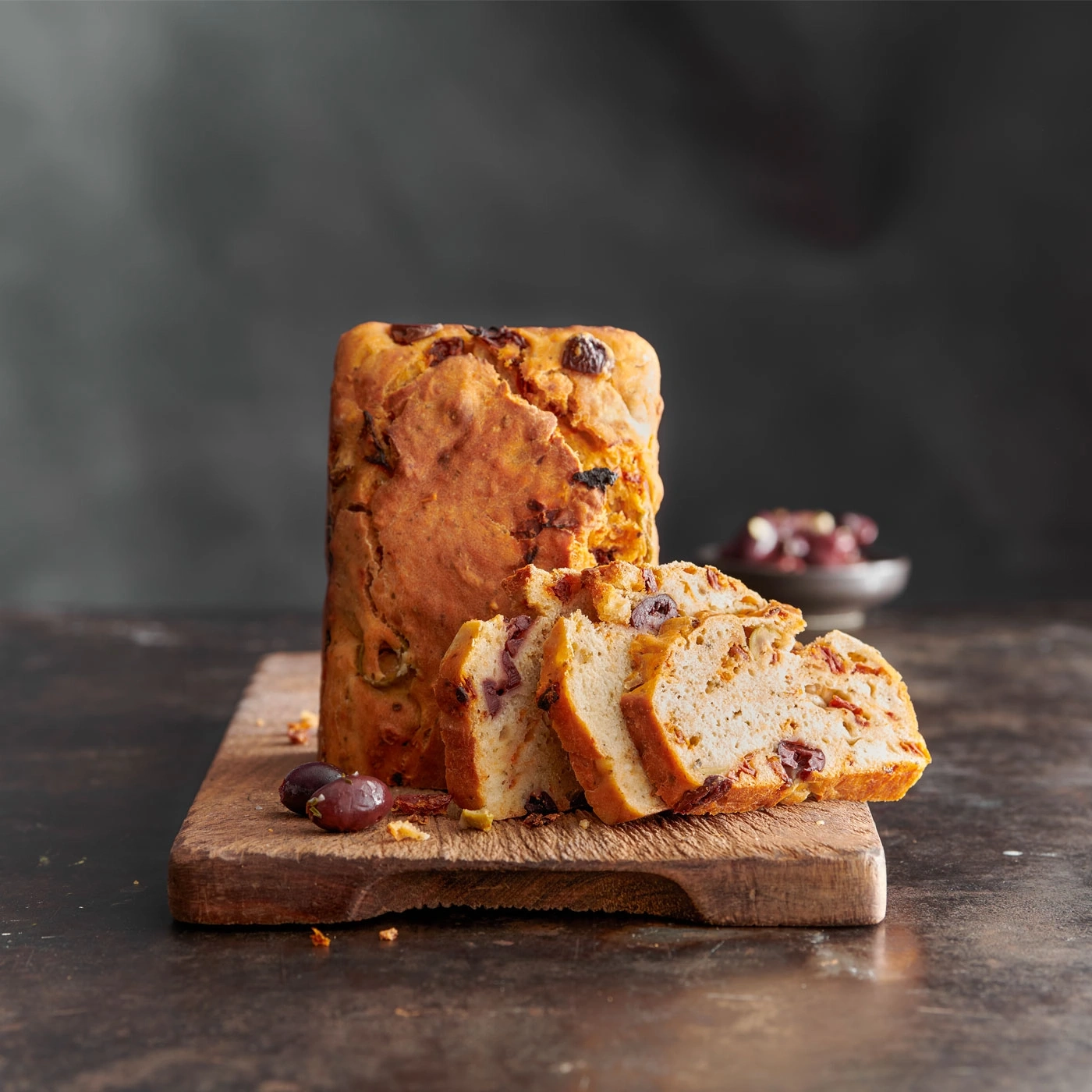Pain aux olives tranché sur une planche en bois, rustique, savoureux, délicieux