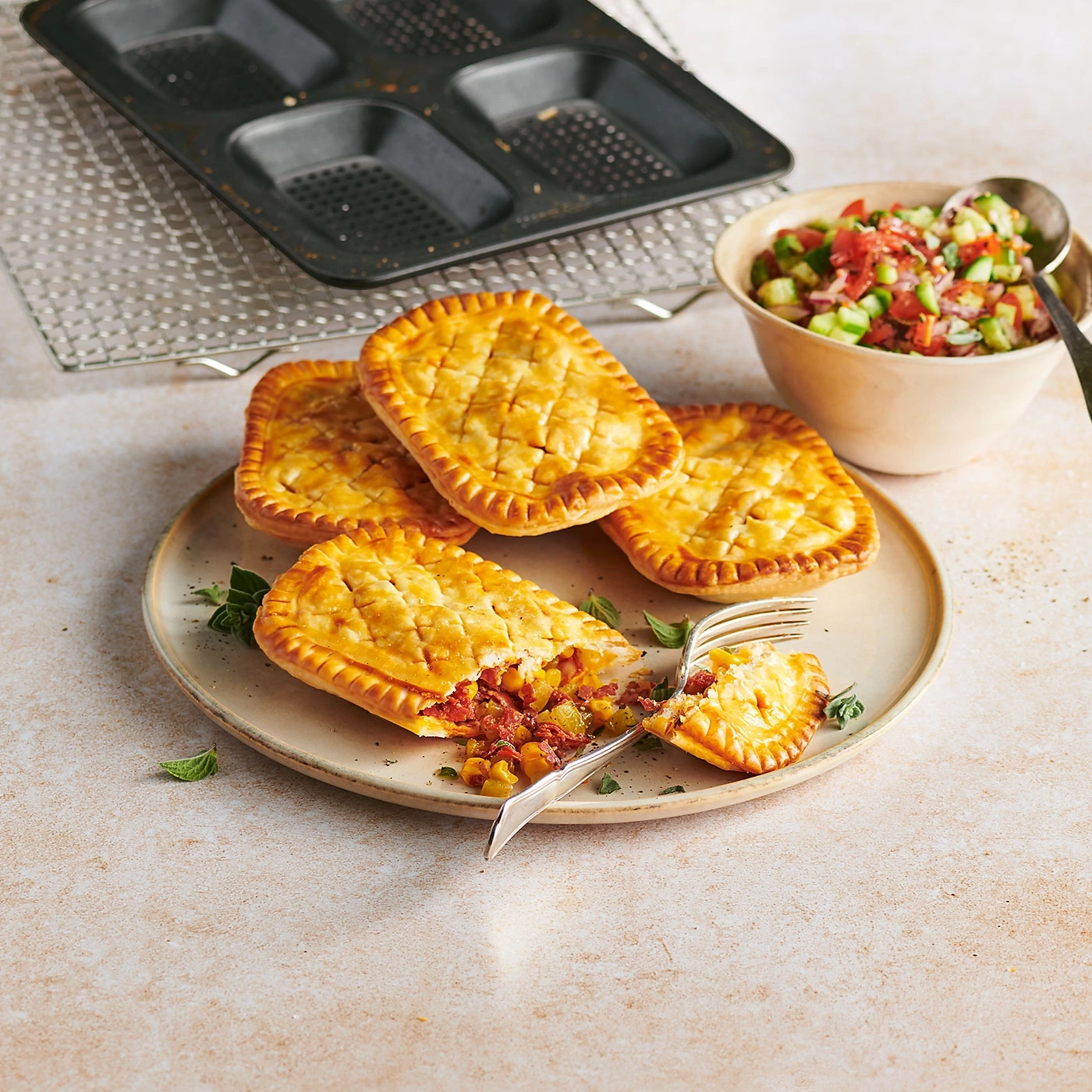 Délicieuses pâtés sur une assiette avec salade d'accompagnement et moule à pâtisserie en arrière-plan.