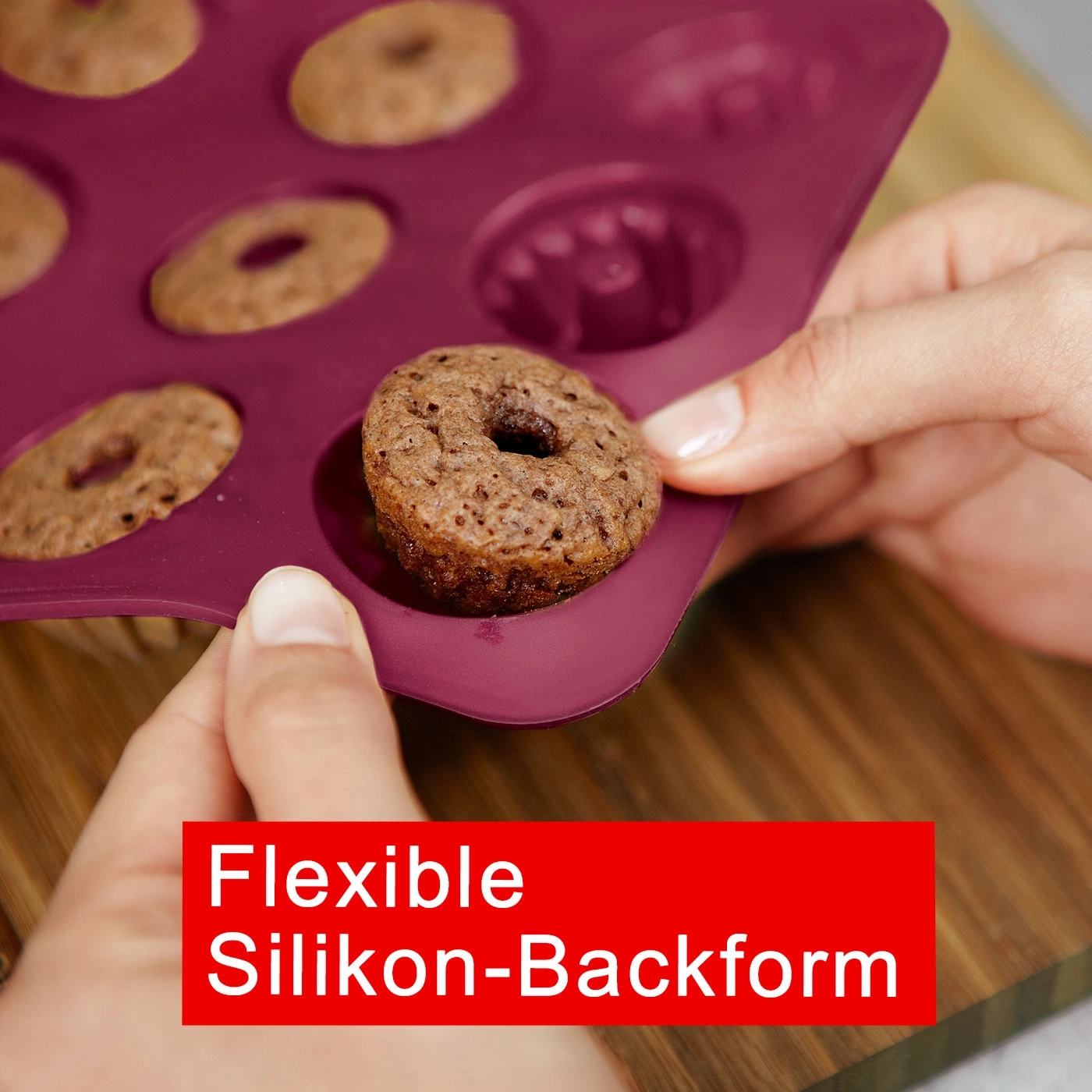 Moule à pâtisserie avec beignets, flexible, silicone, rouge, main, planche de bois, gros plan