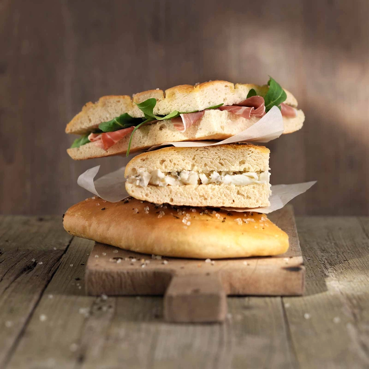 Sandwiches auf Holzbrett. Brot, Käse, Fleisch, Salat. Rustikal, lecker, köstlich, Essen.