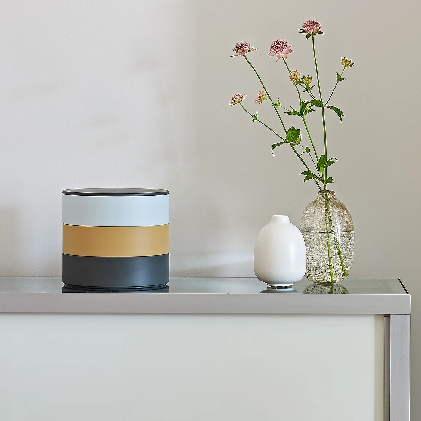 Dekorative Objekte auf einer Kommode: Vase, Blumen, Behälter, minimalistisch, modern.
