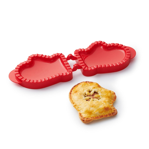 Roter Herz-Teigschneider mit Gebäck, das in Herzform geschnitten wurde.