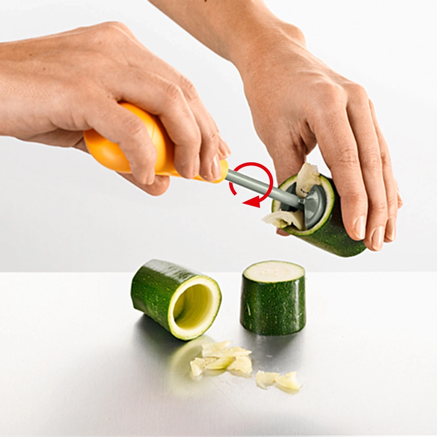 Person verwendet ein Werkzeug, um Zucchini auszuhöhlen, um sie zu füllen.