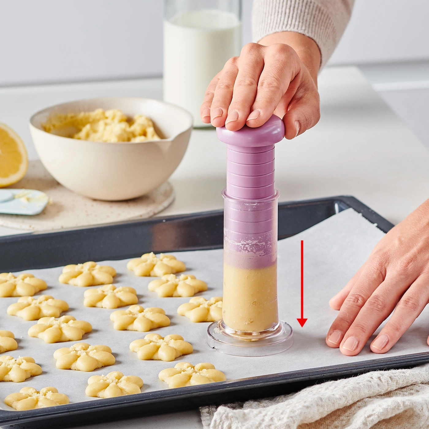 Des biscuits en forme de fleurs sont préparés sur une plaque à pâtisserie avec une poche à douille.