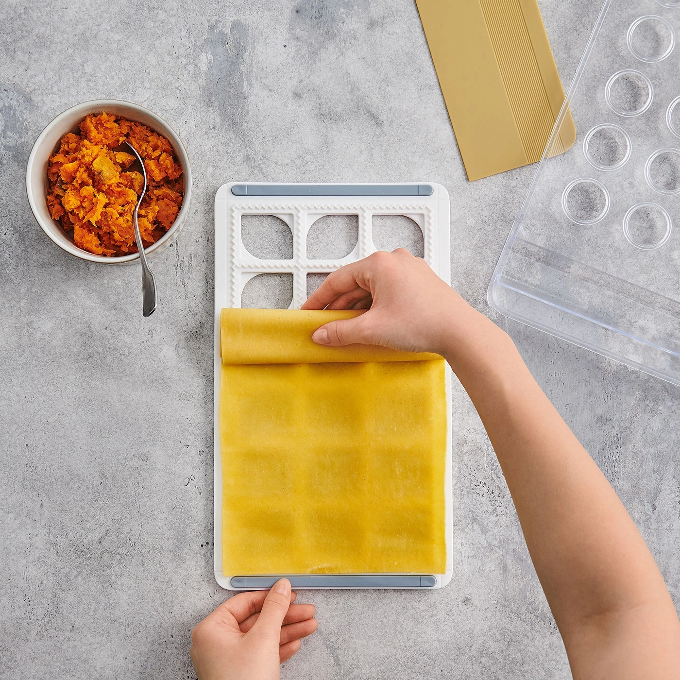 Préparation de raviolis. Pâte, garniture, outils sur fond gris. Cuisine.