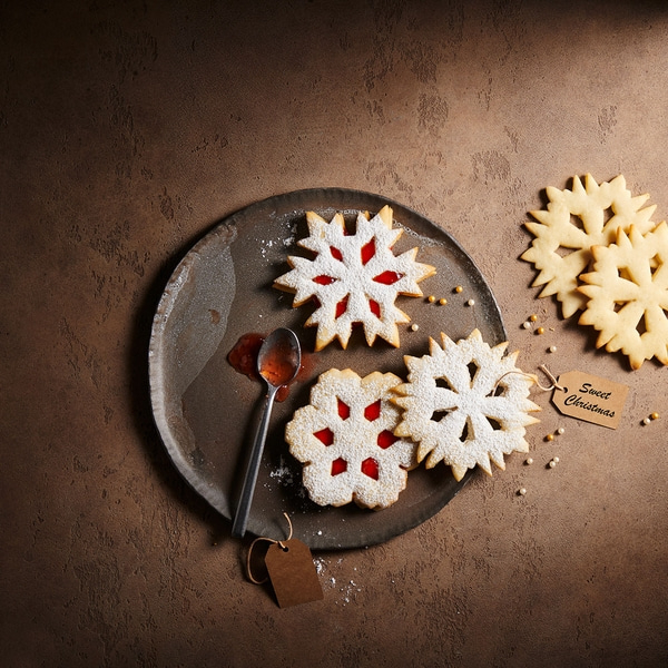Biscuits en forme de flocon de neige avec confiture et étiquette 'Sweet Christmas' sur une assiette.