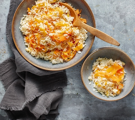 Plat de riz aux carottes dans des bols sur fond gris avec une serviette