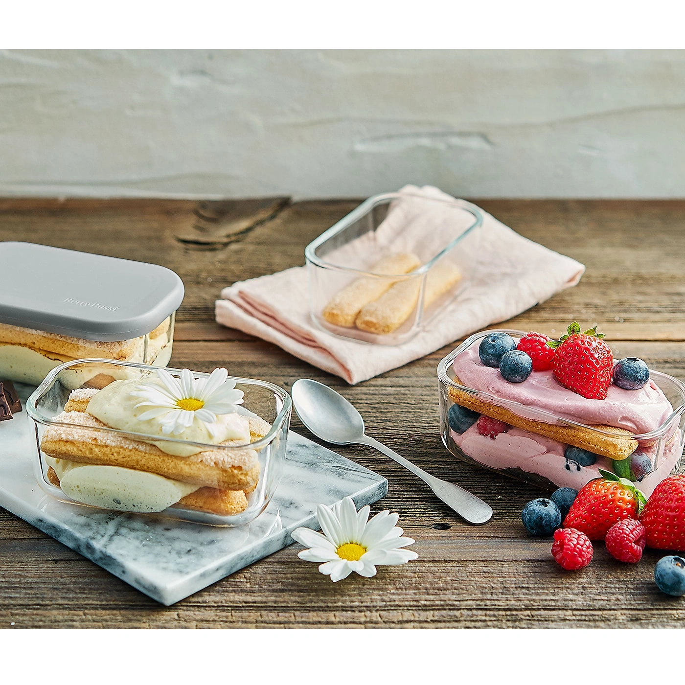 Desserts dans des récipients en verre avec des baies sur une surface en bois, gros plan
