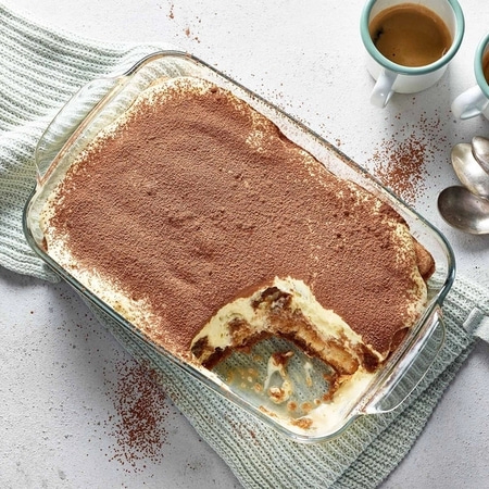 Tiramisu in Glasform, Kaffeetassen und Löffel auf dem Tisch