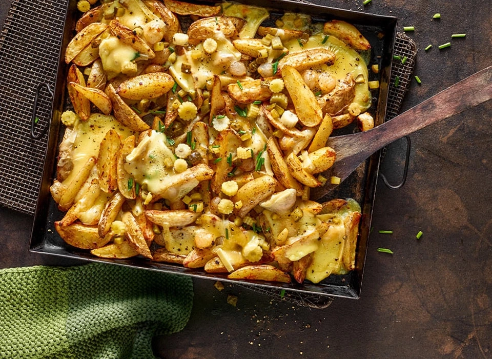 Gebratene Kartoffeln mit Käse und Mais in einer Pfanne, lecker.