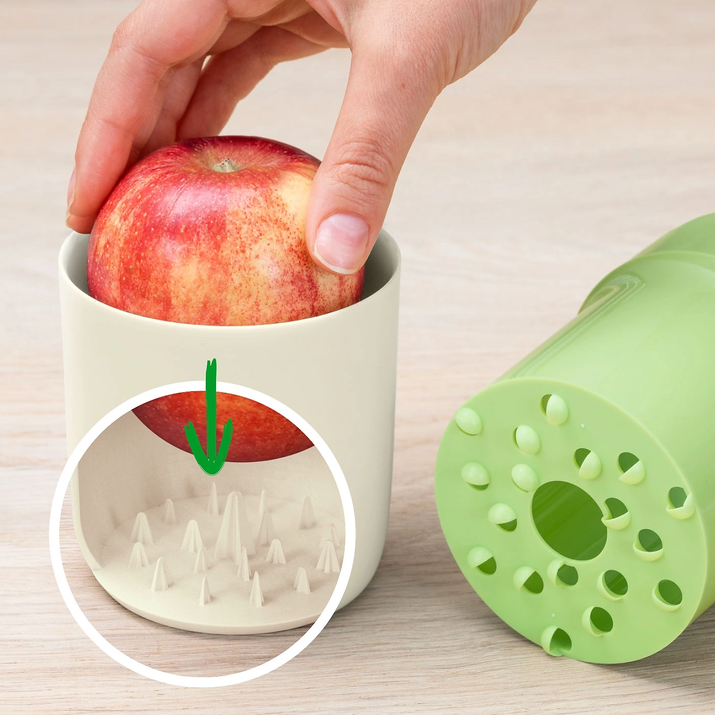 Apfel in einem Behälter mit Stacheln, daneben ein grünes Gerät.
