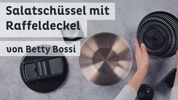 Saladier avec couvercle râpe de Betty Bossi. Ustensiles de cuisine sur fond gris.
