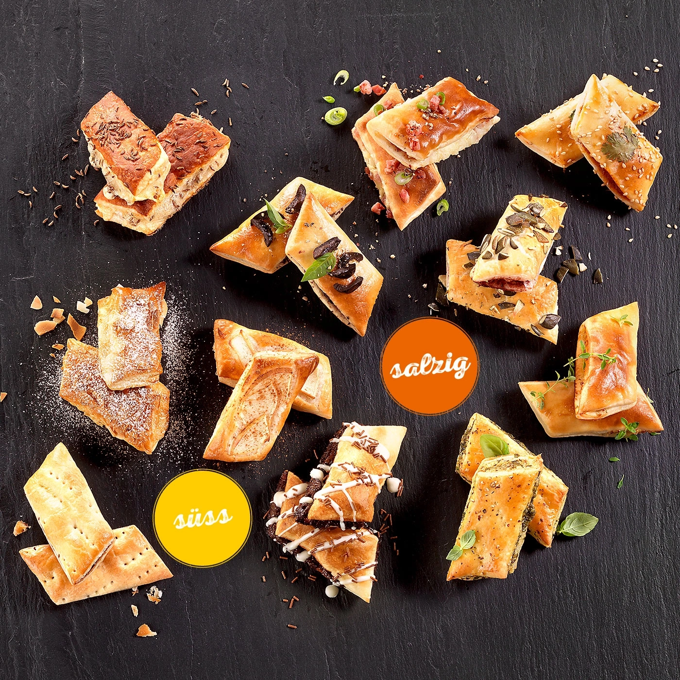 Verschiedene herzhafte und süße Snacks auf schwarzem Untergrund, appetitlich angerichtet.