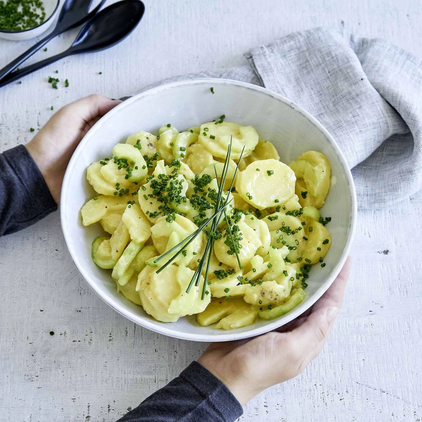 Kartoffelsalat in einer Schüssel, garniert mit frischen Kräutern, serviert