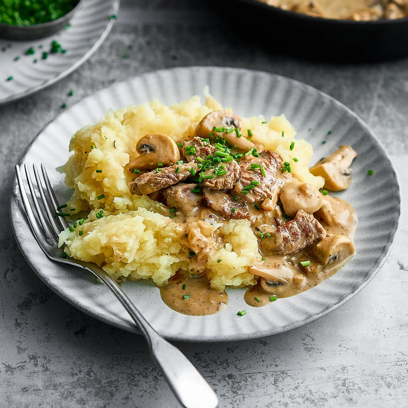 Assiette de purée de pommes de terre, de viande et de champignons, garnie de ciboulette