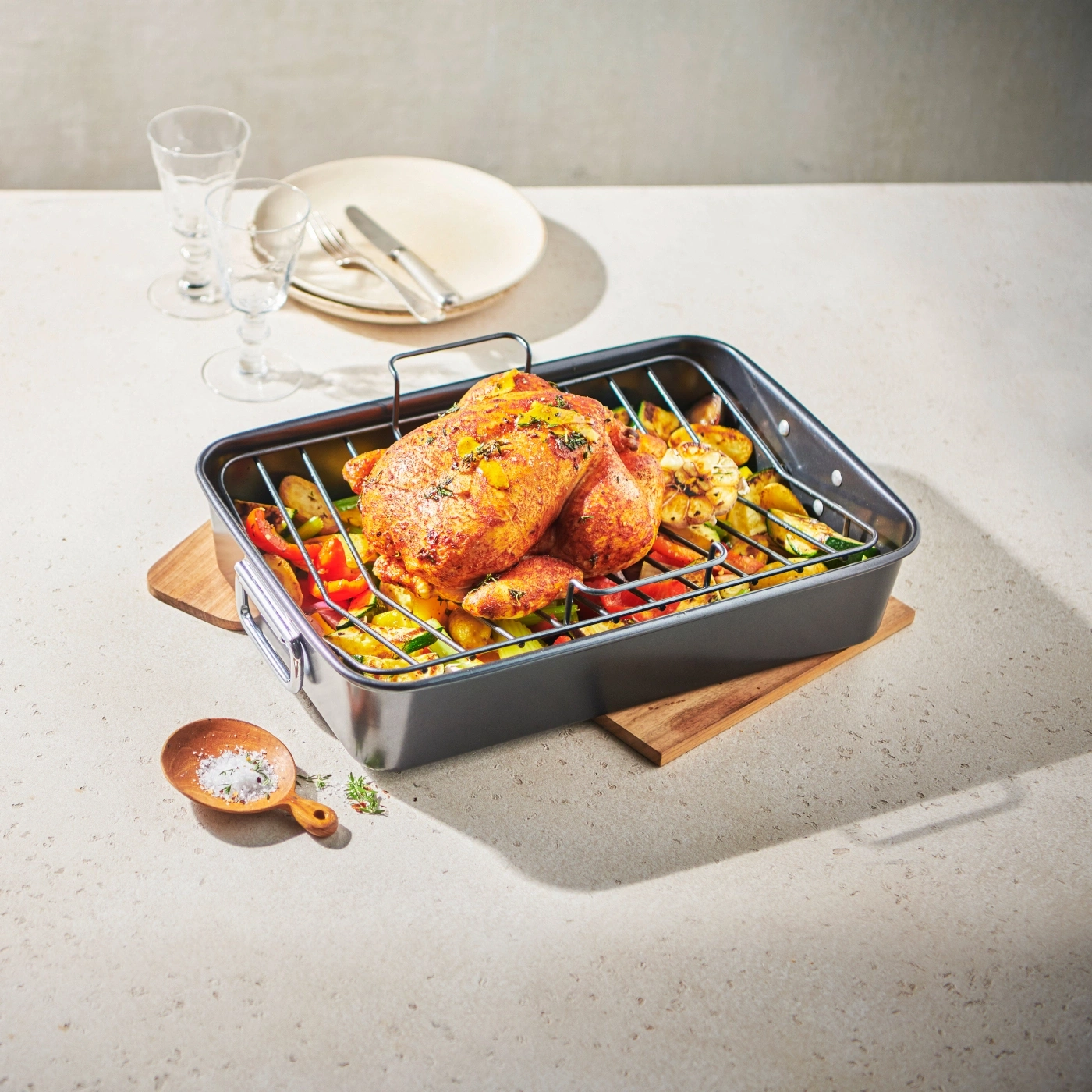 Poulet rôti avec légumes dans un plat sur une table avec couverts et verres