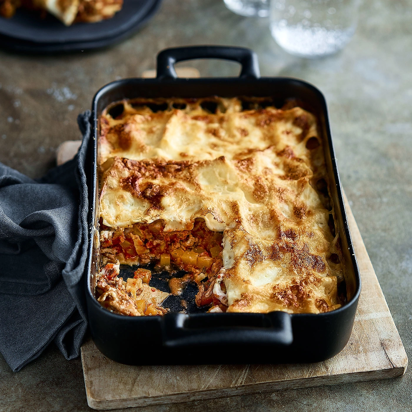 Lasagnes dans un plat noir sur une planche de bois, délicieux et savoureux