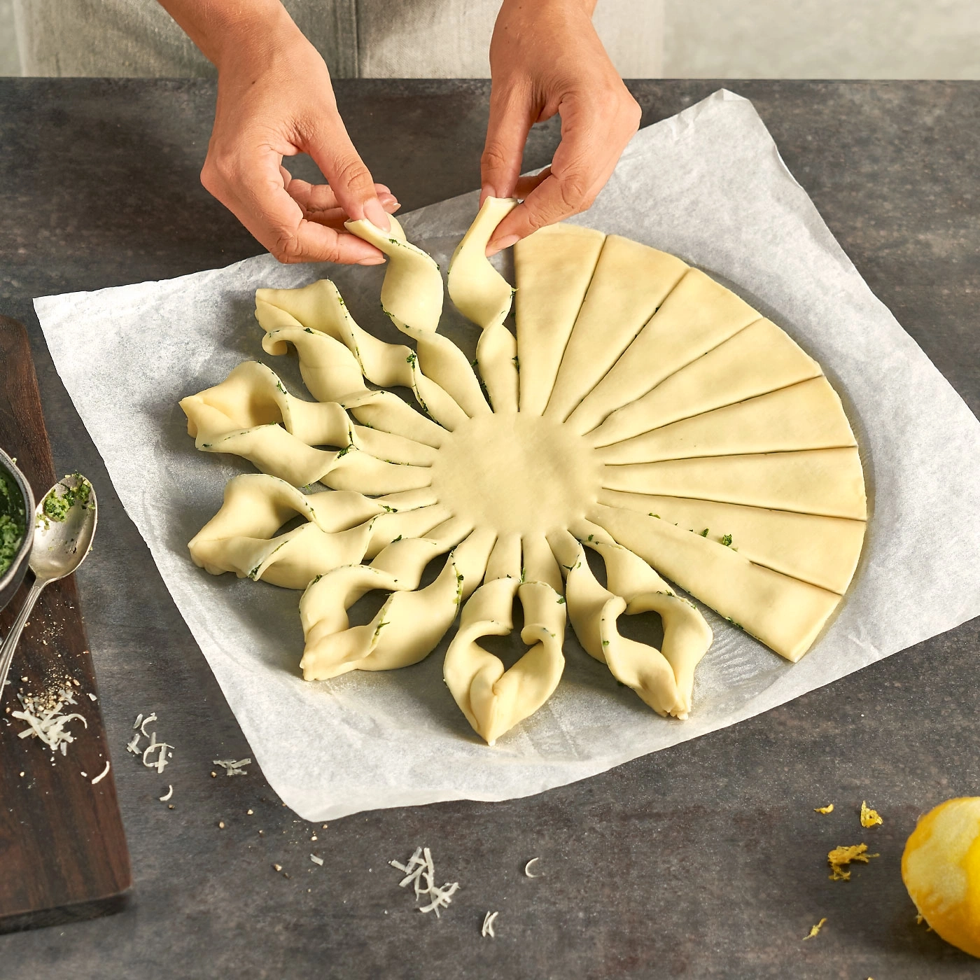 Personne façonnant une pâte à pâtisserie en forme de soleil sur du papier sulfurisé.