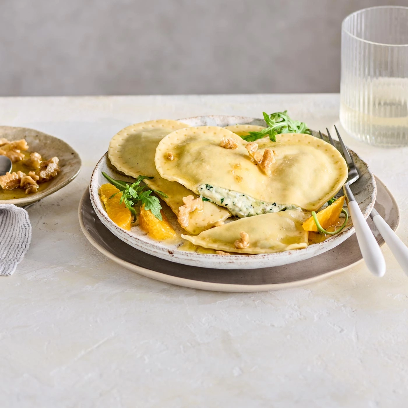 Plat de raviolis avec des oranges et des noix, gros plan sur une assiette.