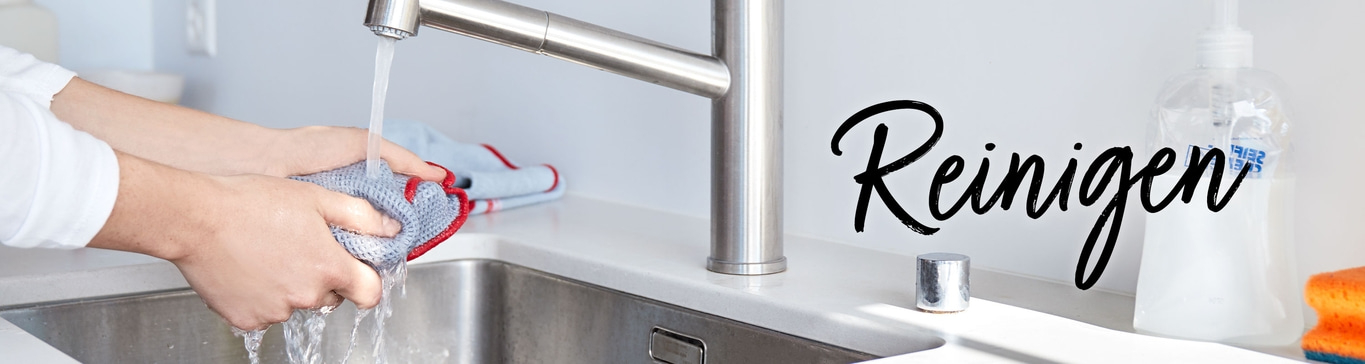 Person wäscht einen Lappen unter fließendem Wasser in der Küche.