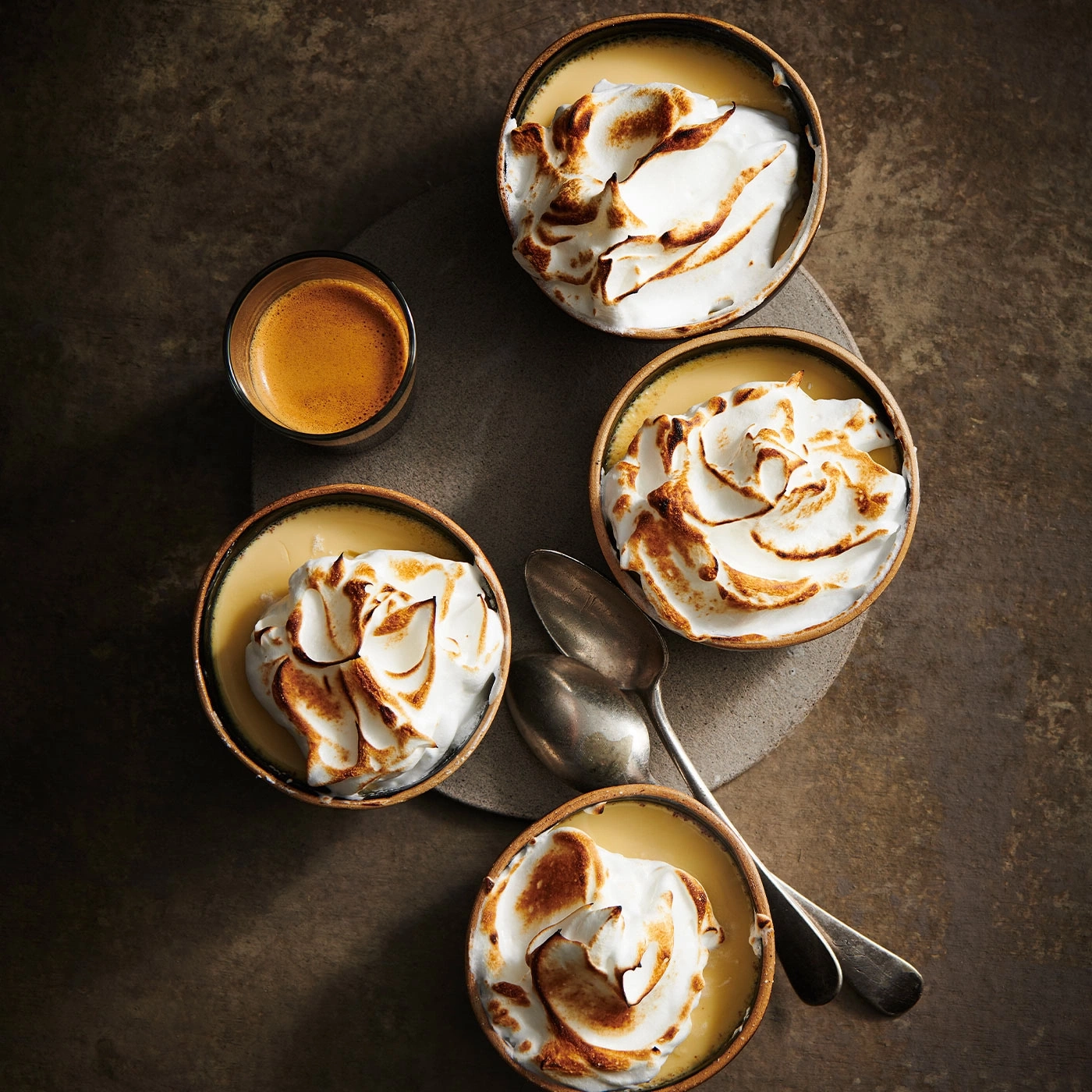 Desserts mit Baiser, Espresso, Löffel auf einem grauen Untergrund