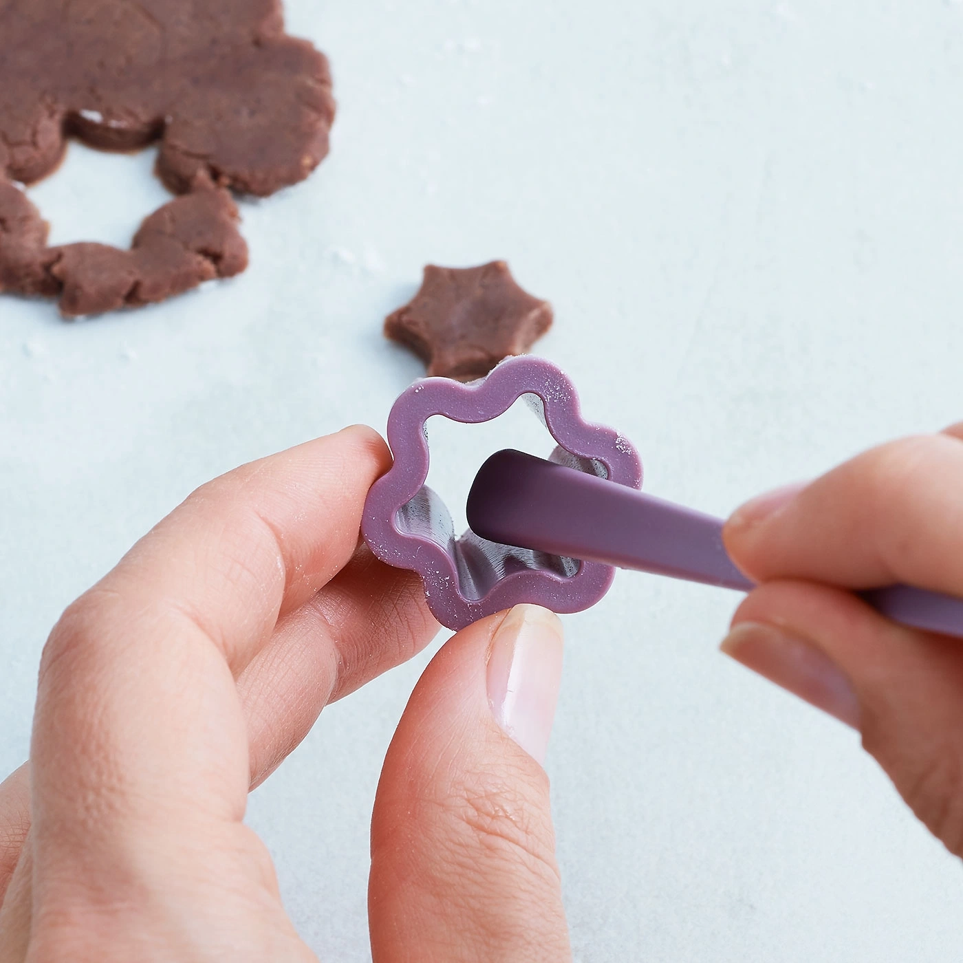 Personne coupant des biscuits avec un emporte-pièce dans la pâte, gros plan, mains