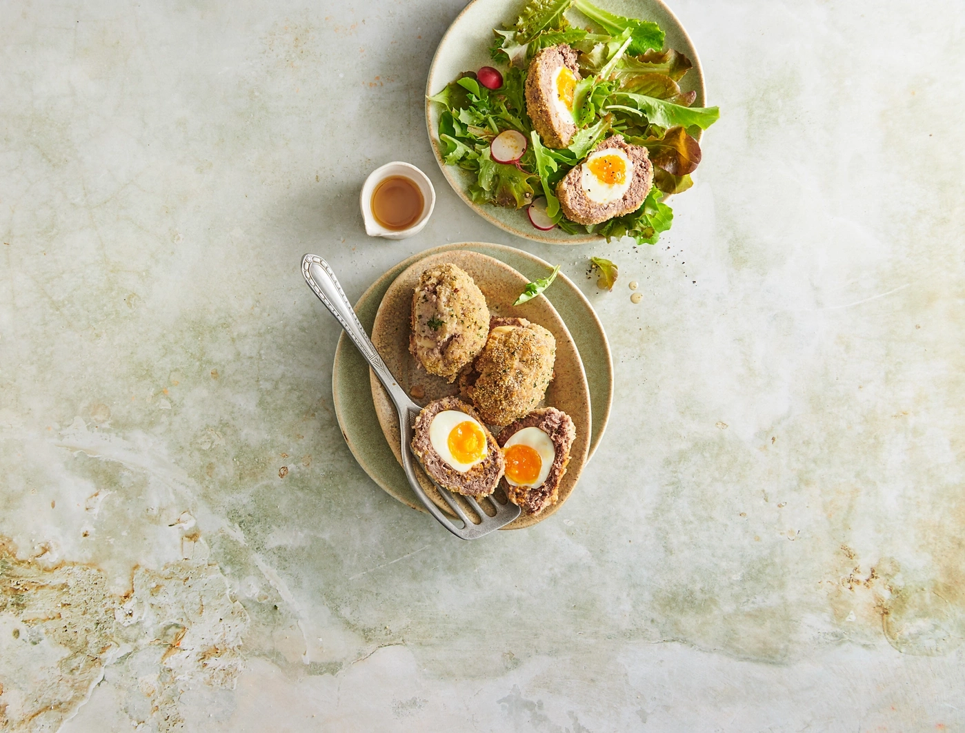 Schottische Eier mit Salat und Soße auf einem Teller, Nahaufnahme