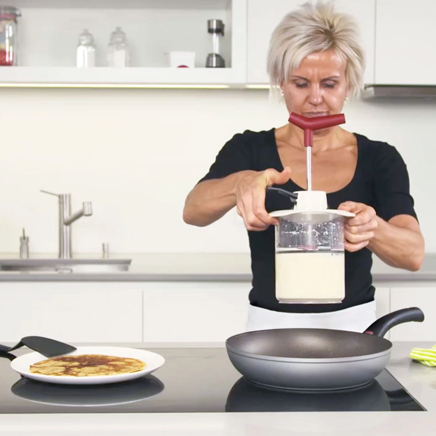 Frau macht Pfannkuchen in der Küche mit einem speziellen Gerät.