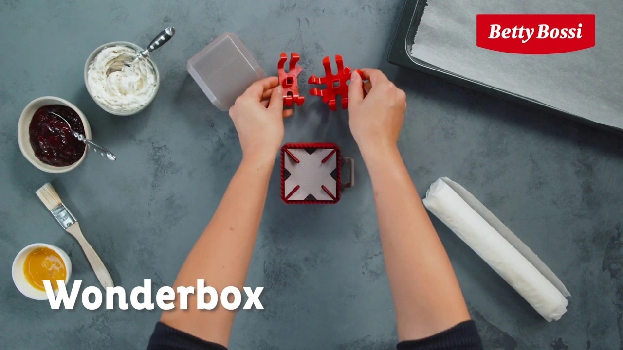 Wonderbox-Zubehör mit Zutaten und Backblech auf grauem Hintergrund.