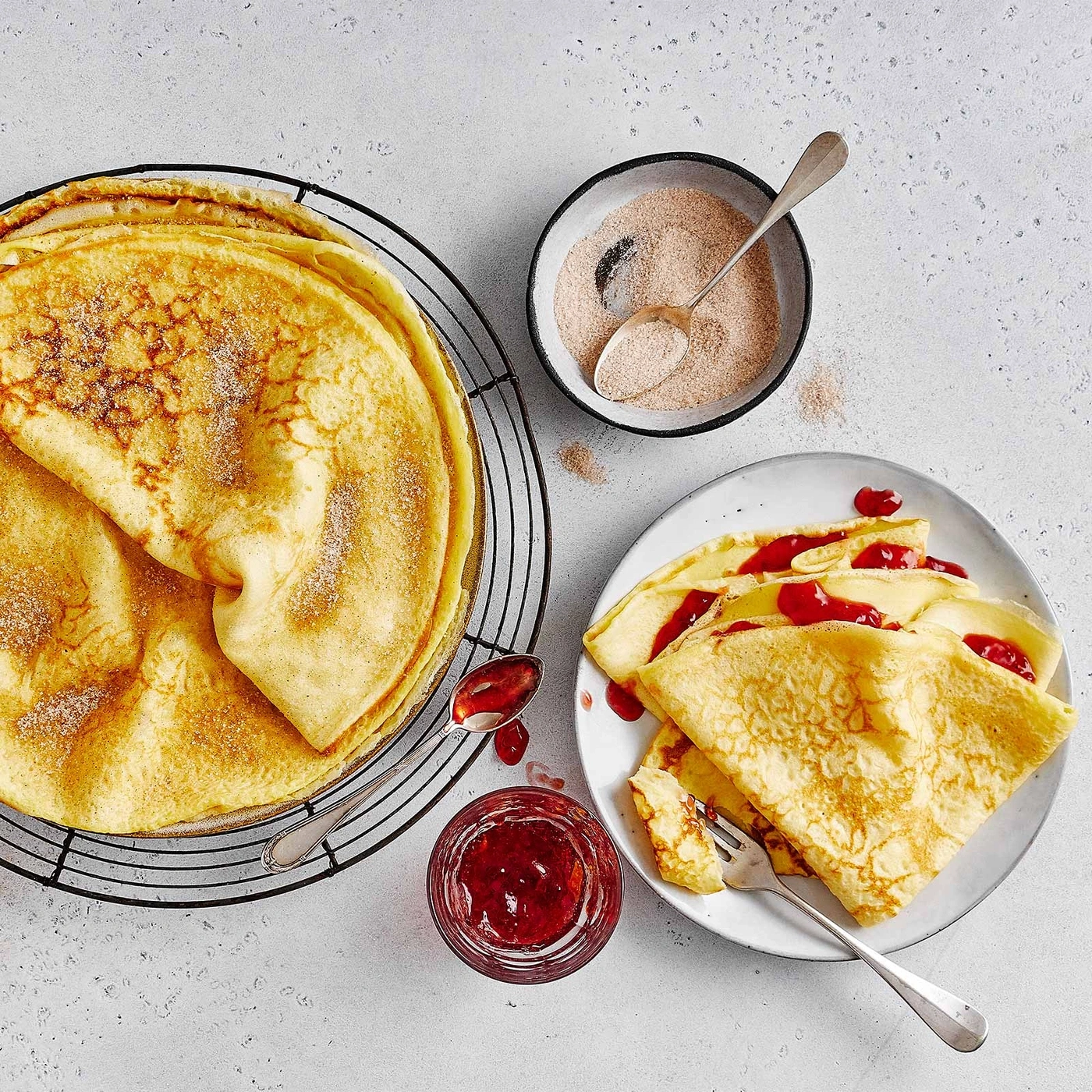 Pfannkuchen mit Marmelade und Zimtzucker, serviert auf einem Teller und einem Gitter