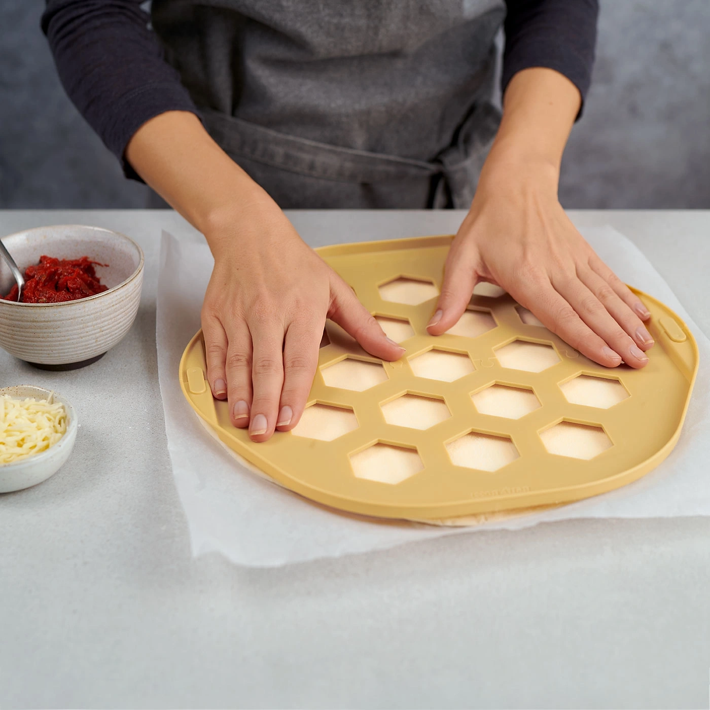 Personne préparant une pizza avec des ingrédients et un outil spécial.