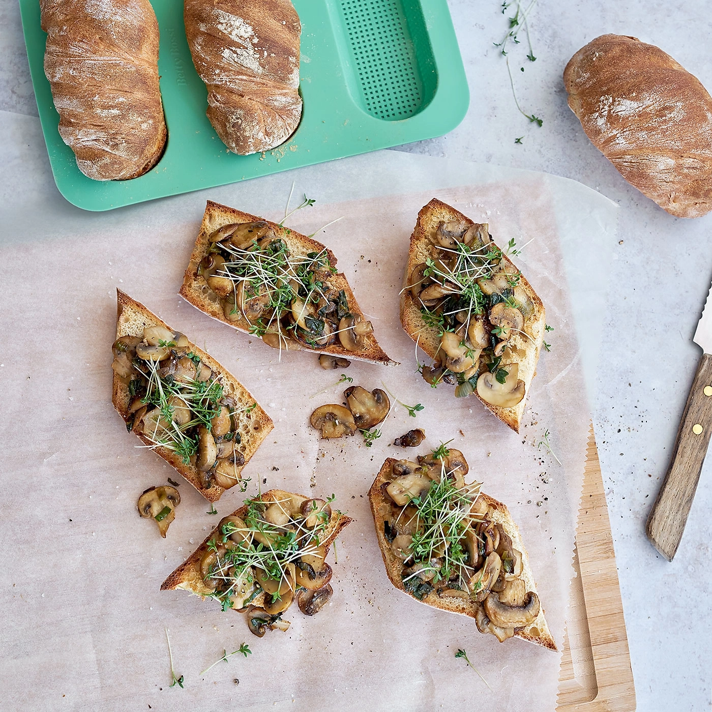 Geröstetes Brot mit Pilzen und Kräutern, auf einem Brett serviert.