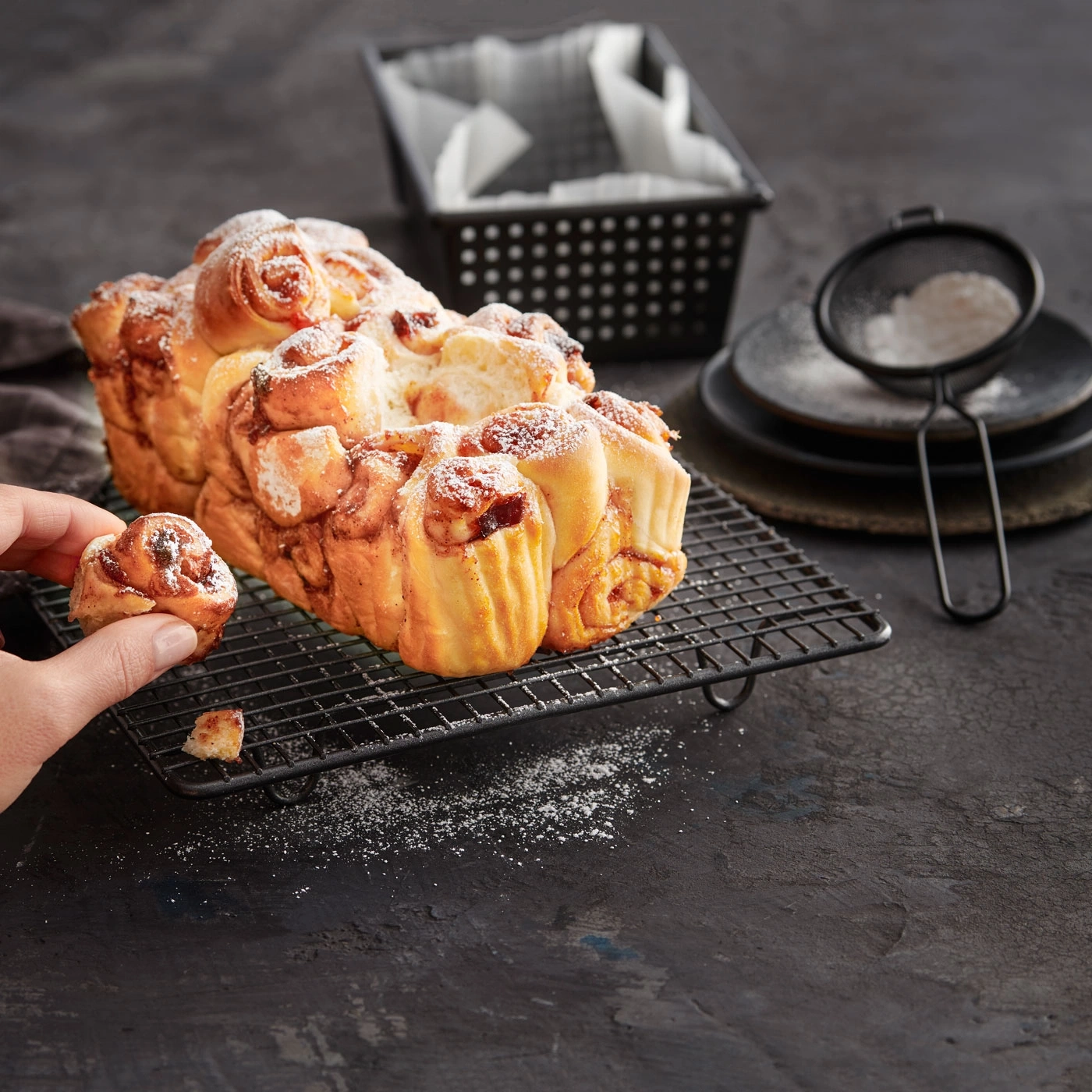 Gros plan sur des brioches à la cannelle saupoudrées de sucre glace sur une grille.