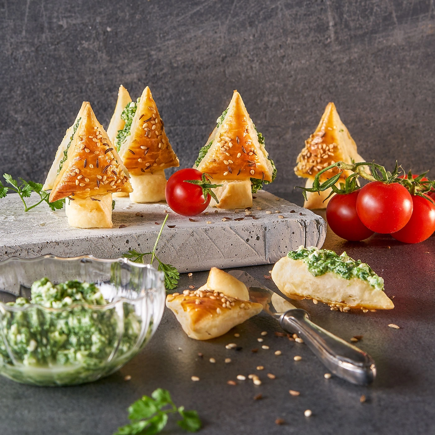 Köstliche, weihnachtliche Appetithäppchen mit Tomaten und Kräutern auf einem grauen Hintergrund.