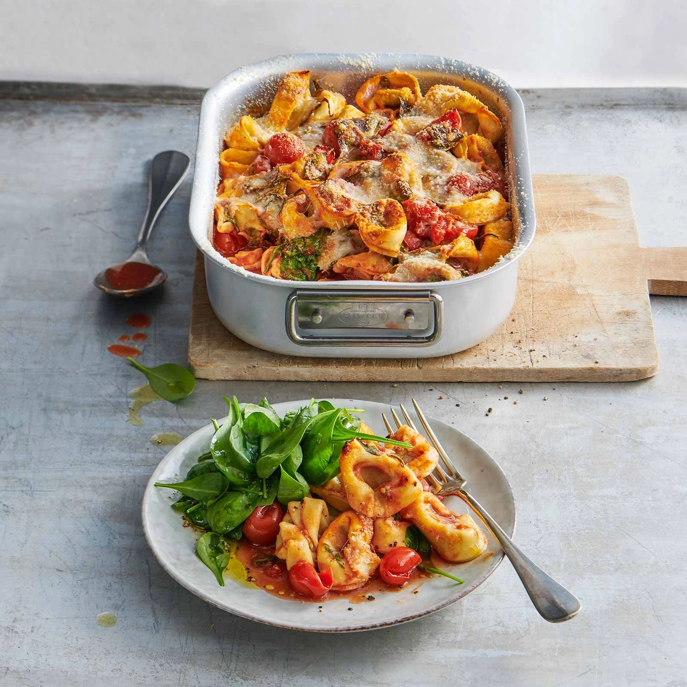 Tortellini-Auflauf mit Tomaten und Spinat auf einem Teller und in einer Auflaufform