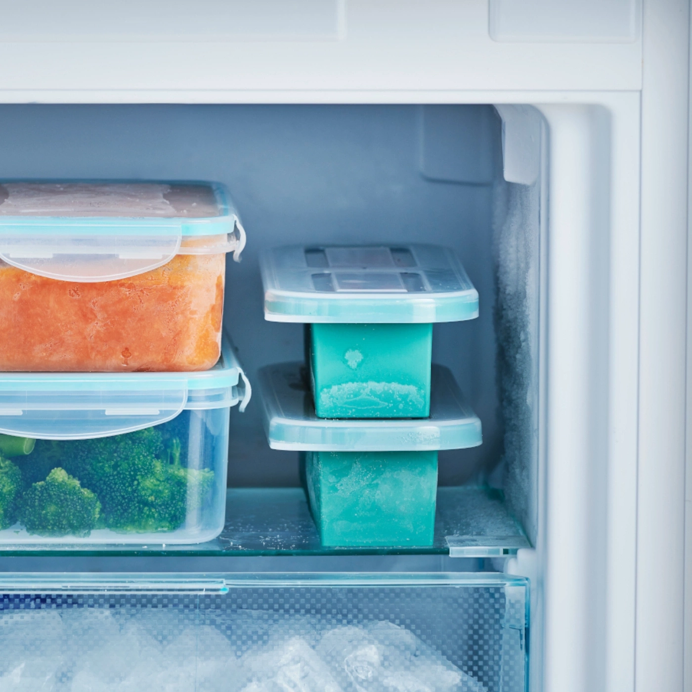 Kühlschrank mit Behältern, gefrorenem Gemüse und Eiswürfeln. Lebensmittelaufbewahrung.