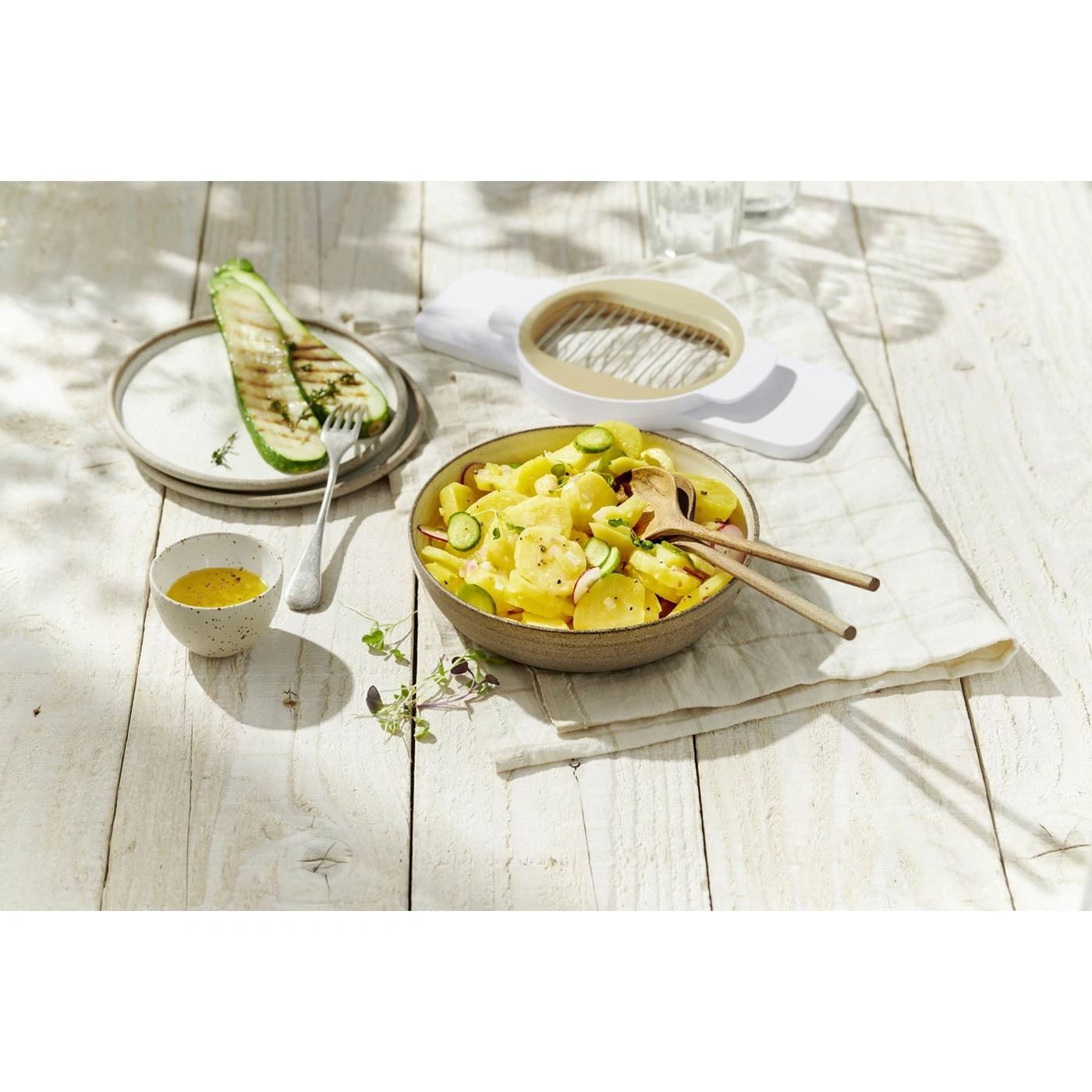 Kartoffelsalat mit gegrilltem Gemüse und Dressing auf einem Holztisch