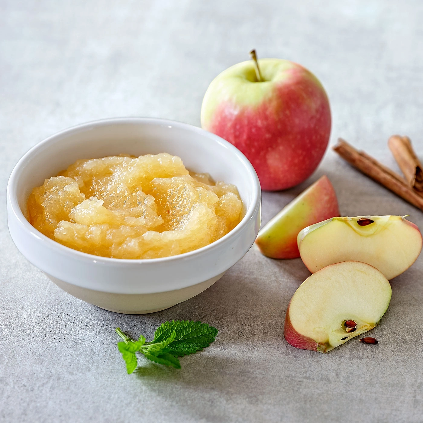 Compote de pommes dans un bol avec des tranches de pomme et des bâtons de cannelle