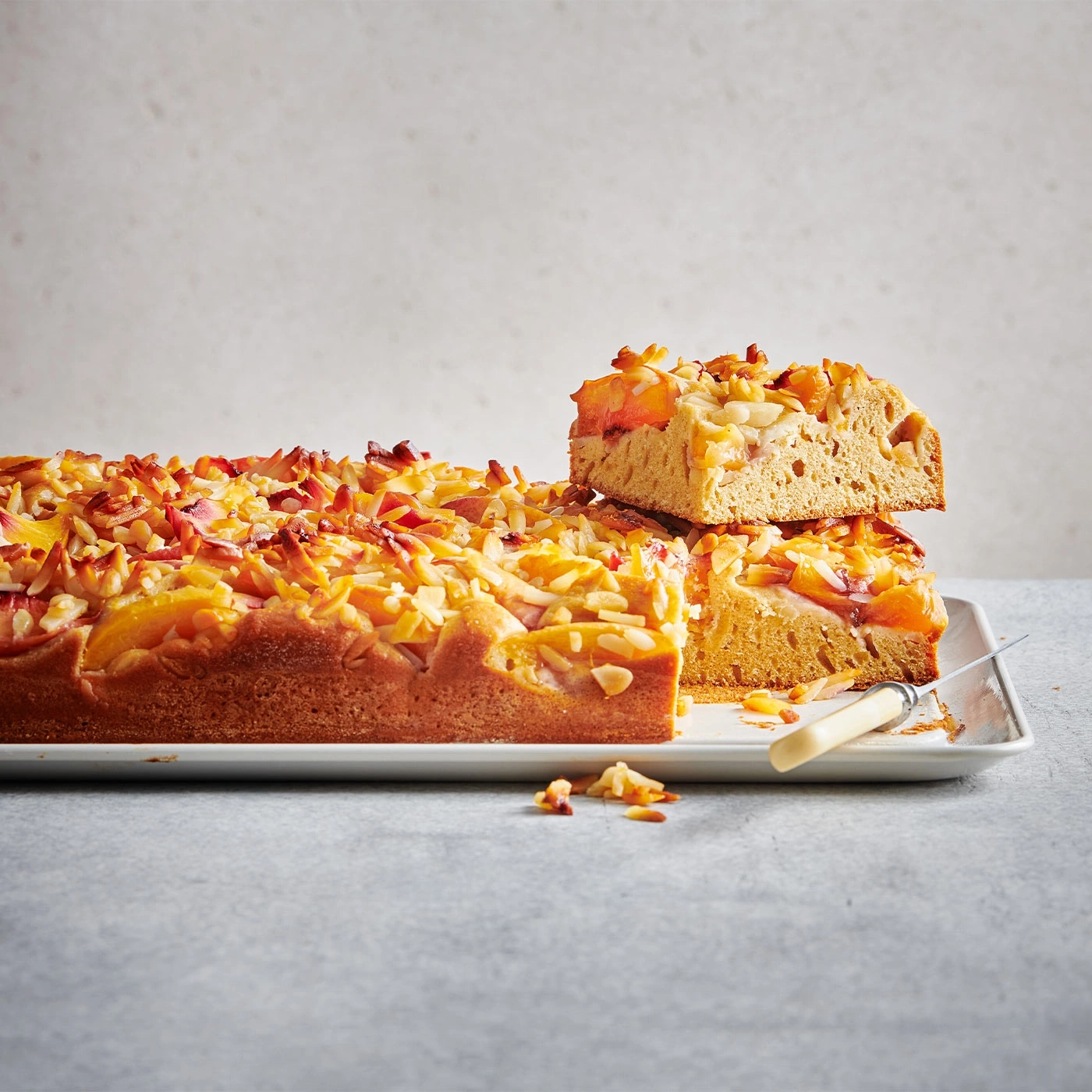 Kuchen mit Pfirsichen und Mandeln, auf einer Platte, angeschnitten