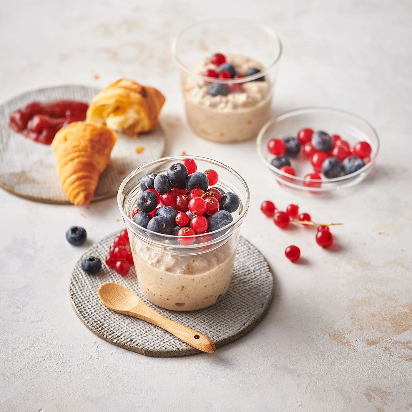 Frühstück mit Beeren, Croissant und Marmelade auf hellem Hintergrund