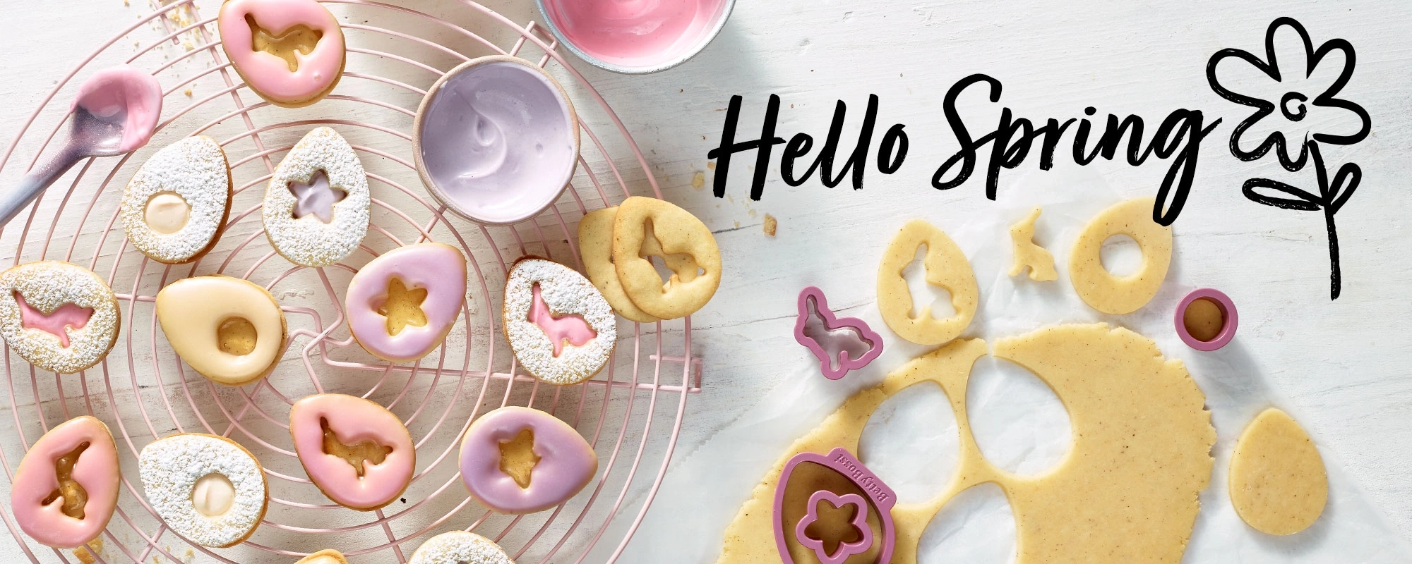 Osterkekse mit Zuckerguss und Ausstechern auf einem Gitter, 'Hello Spring'.