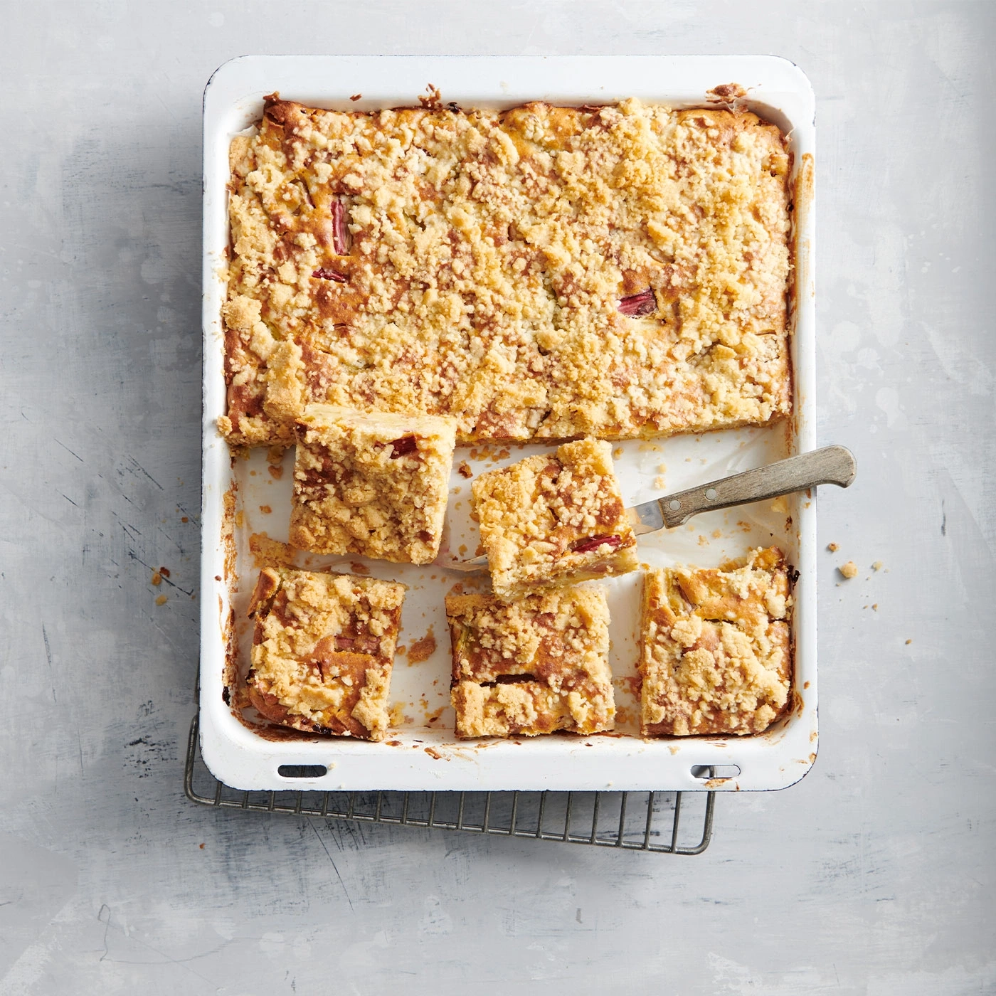 Kuchen in einer Backform, geschnitten, mit Streuseln, auf einem Rost.