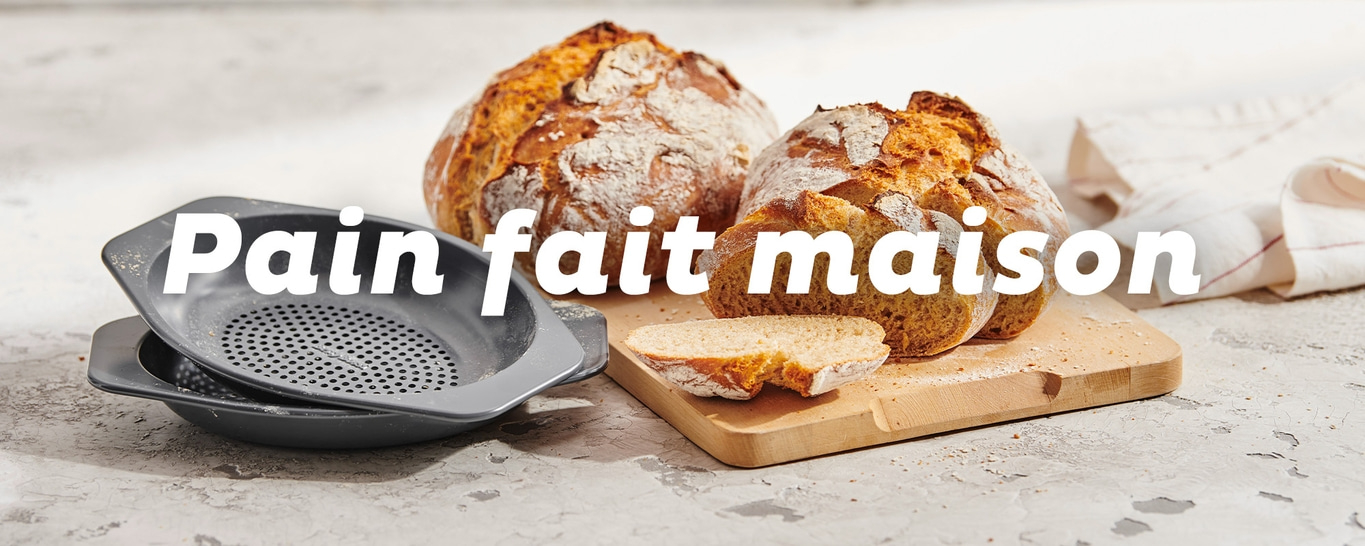 Deux pains faits maison sur une table en bois avec une passoire.