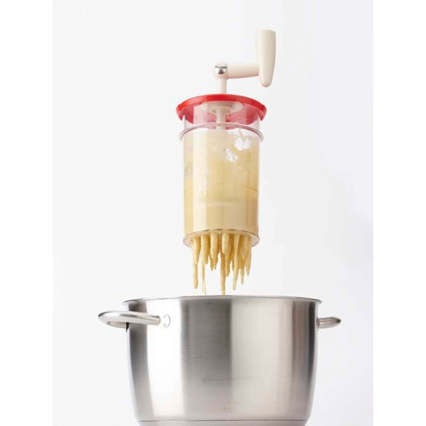 Machine à pâtes laissant tomber des nouilles dans une casserole, gros plan.